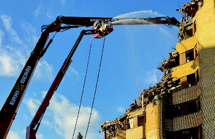 Bombeo y máquina telescópica articulada con mangueras para regar sobre la zona a demoler