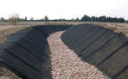 Channelling of the Rejas Stream, with gravel at the channel bottom and slopes upholstered with geogrid hydro-seeded.